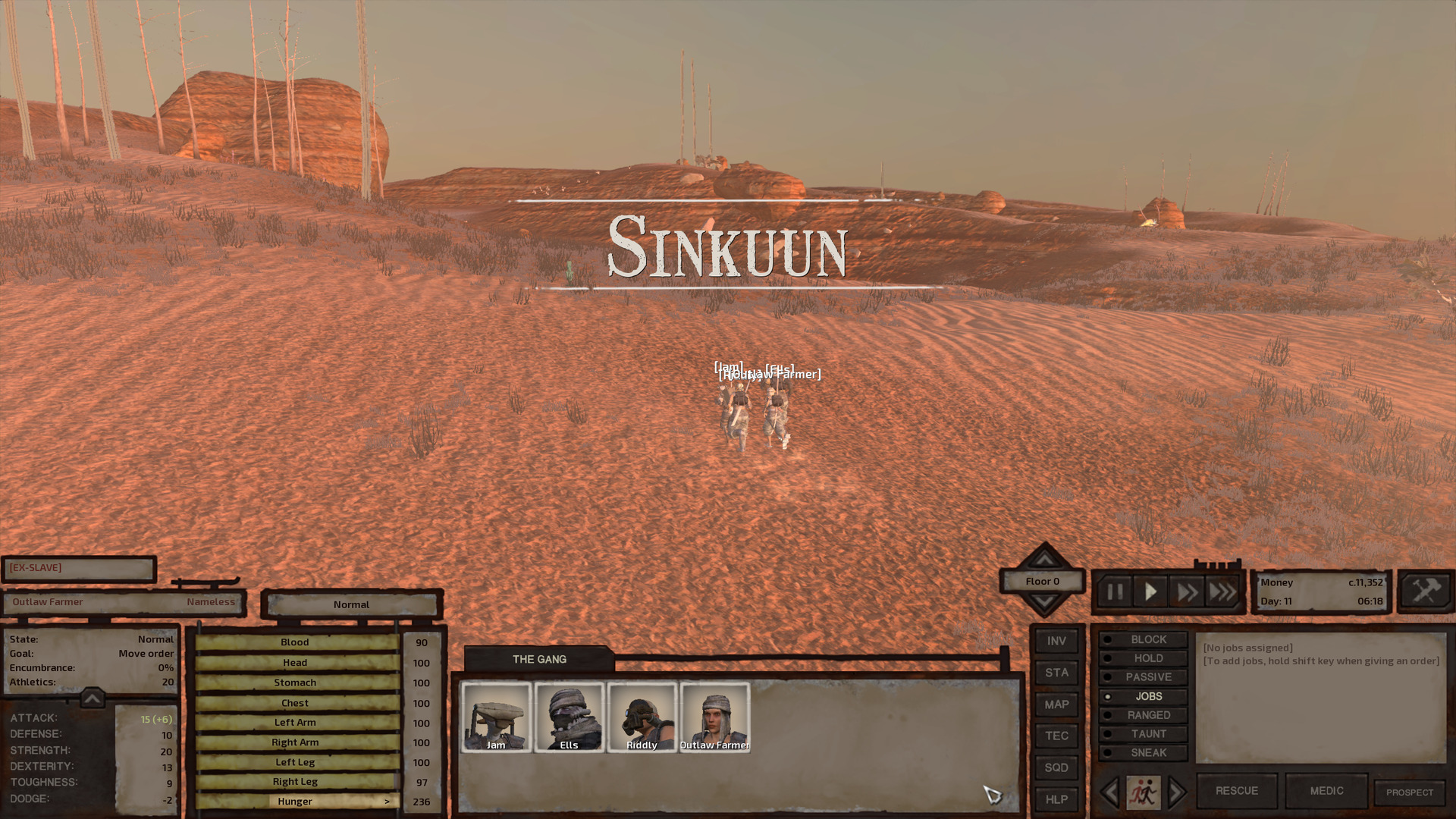 The gang walks across orange desert sand. In front of them, the landscape changes from desert to badlands.