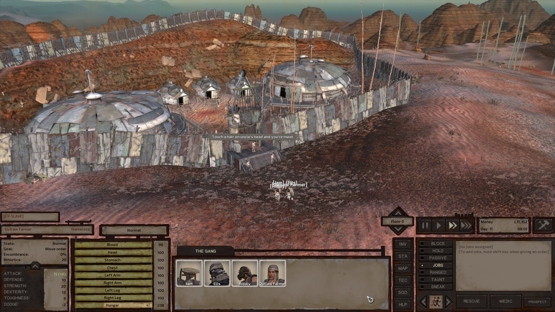 A small settlement, protected by crappy walls made from overlapping sheets of scrap metal topped with barbed wire. The settlement consists of a few small shacks and a couple larger circular buildings similarly made of overlapping metal sheets. The gate guard hurls a threat at the gang.